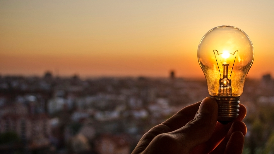 Sunrise shining through a lightbulb held against the landscape